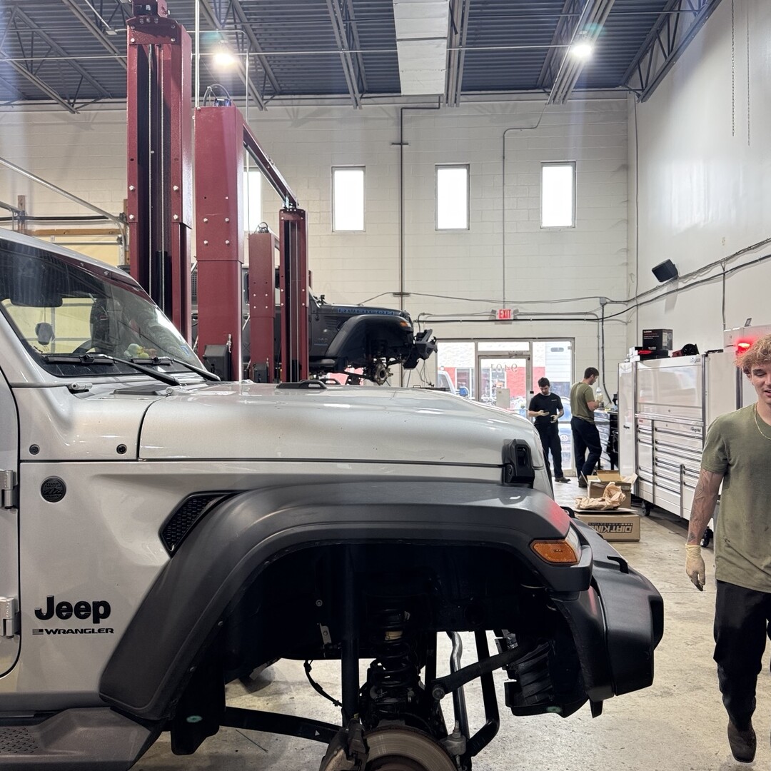 Jeep with its front wheel removed in the service bay